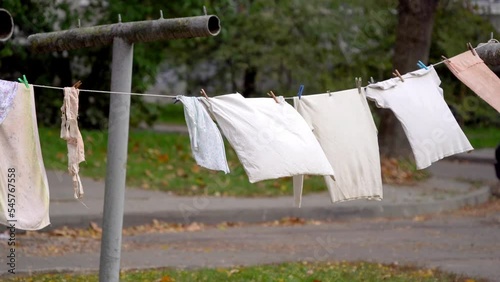 Old light colored clothes dry on a rope and sways in the wind in the yard - poverty in the city photo