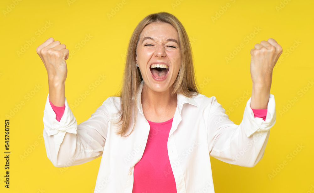 Enthusiastic charming woman rejoicing, say yes, looking happy and celebrating victory, champion dance, fist pump gesture, standing over yellow background. Woman in white shirt winner Enthusiastic charming woman rejoicing, say yes, looking happy and celebrating victory, champion dance, fist pump gesture, standing over yellow background. Woman in white shirt winner