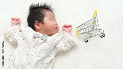 産後1か月0歳の新生児の横に買い物のカートを配置した動画 photo