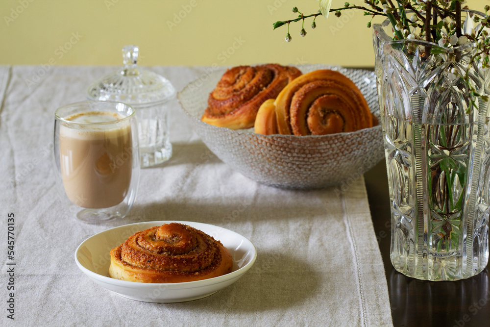 Cinnamon buns with nuts served with cappuccino on a linen tablecloth. Useful breakfast.