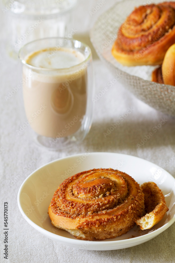 Cinnamon buns with nuts served with cappuccino on a linen tablecloth. Useful breakfast.