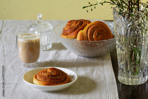 Obraz na płótnie Cinnamon buns with nuts served with cappuccino on a linen tablecloth. Useful breakfast. w salonie