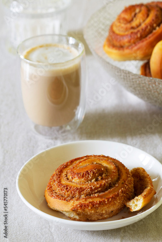 Obraz na płótnie Cinnamon buns with nuts served with cappuccino on a linen tablecloth. Useful breakfast. w salonie