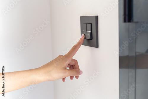 Close up of young woman's hand raising the blinds in her room with a button 