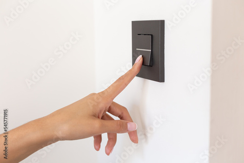 Close up of young woman's hand pressing the light switch button