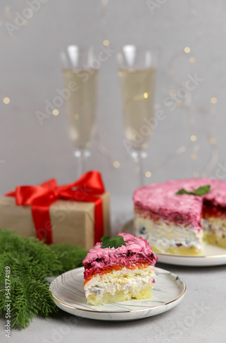 Traditional Russian New Year's salad, herring under a fur coat on a white plate on a gray background. Russian national cuisine. Selective focus