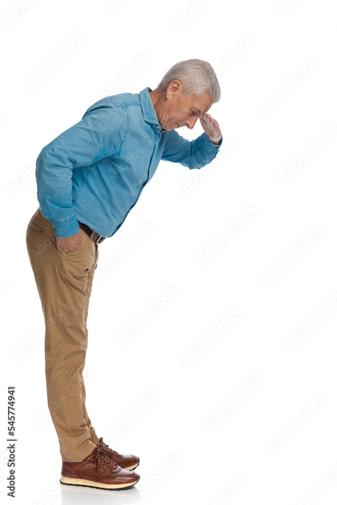 side view of handsome old guy holding hand to forehead and looking down side view of handsome old guy holding hand to forehead and looking down