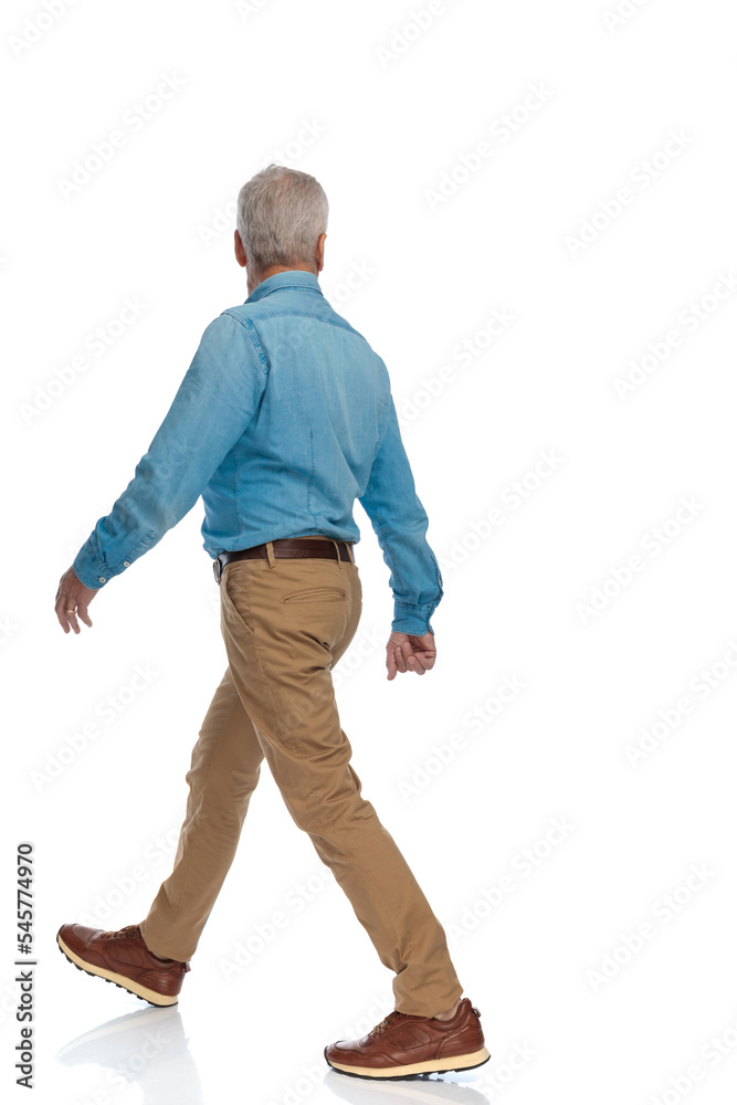 side view of casual old man with sneakers looking away and walking side view of casual old man with sneakers looking away and walking