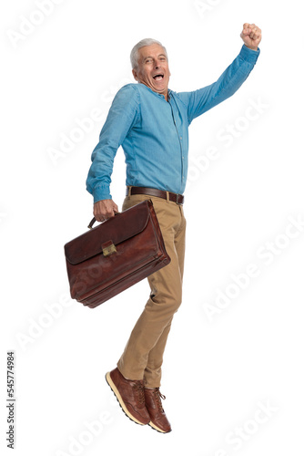 excited man with grey hair holding suitcase and jumping in the air photo