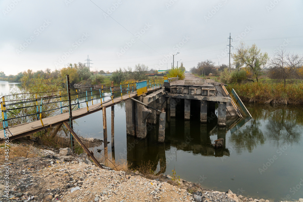 Destroyed bridge across the river. War in Ukraine. Russian invasion of Ukraine. Destruction of infrastructure. Terror of the civilian population. War crimes