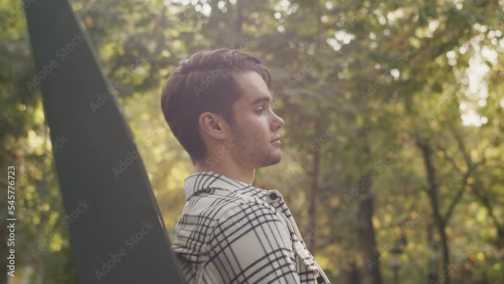 Handsome caucasian man sits on a bench in the park alone, sighs, unrecognizable female in black jacket, comes up from behind, closes his eyes with her hands. Guess who, surprise concept Handsome caucasian man sits on a bench in the park alone, sighs, unrecognizable female in black jacket, comes up from behind, closes his eyes with her hands. Guess who, surprise concept