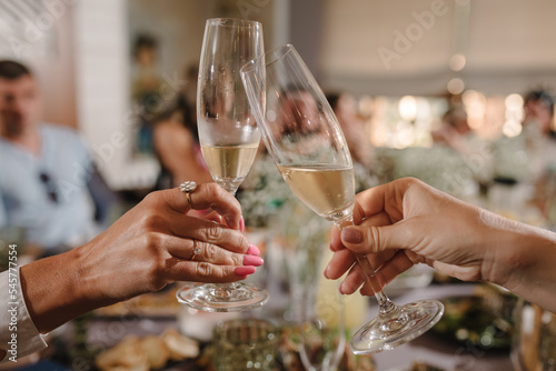 Young bridesmaids clinking with glasses of champagne in hotel room. Closeup photo of cheerful girls celebrating a bachelorette party. Females have toast with wine. Celebration. Bachelorette party.