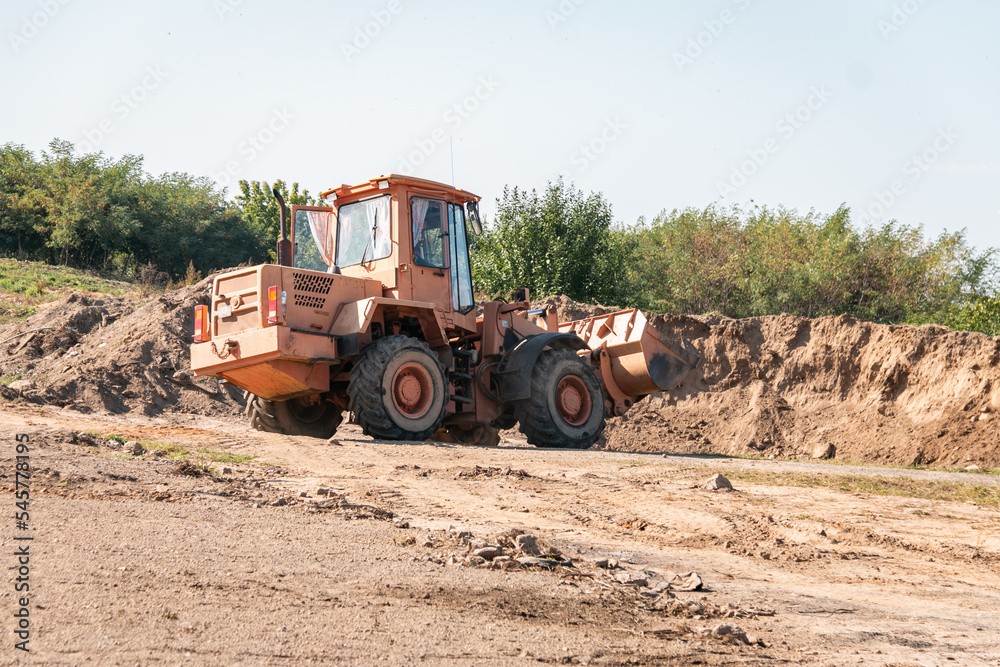 Wheeled tractor bulldozer drips the earth in the quarry. Construction works.