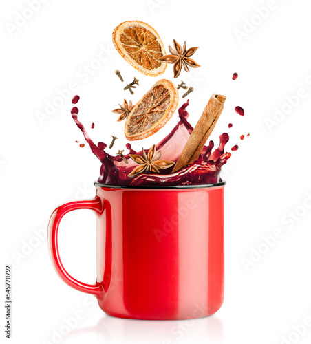 Photos a splash of mulled wine, falling into a red mug of cinnamon, cloves, dried orang