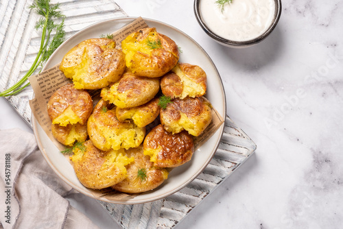 Fotografi smashed potato on parchment paper with garlic sauce