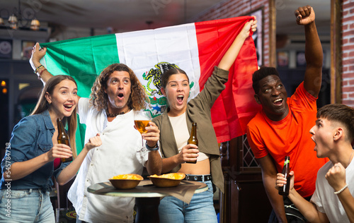 Joyful fans of the Mexican team celebrating the victory in the night bar