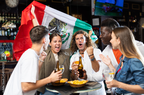 Joyful fans of the Mexican team celebrating the victory in the night bar