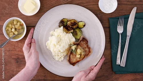 Serving a Plate of Pork Chops with Apples and Brussel Sprouts photo