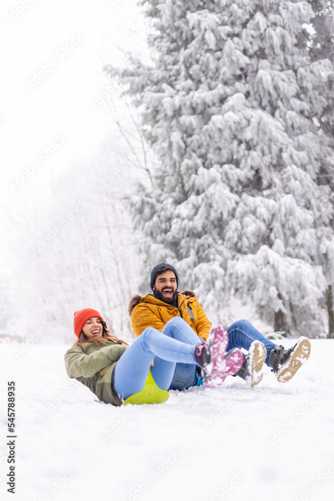 Couple sliding down the hill while on winter vacation Couple sliding down the hill while on winter vacation