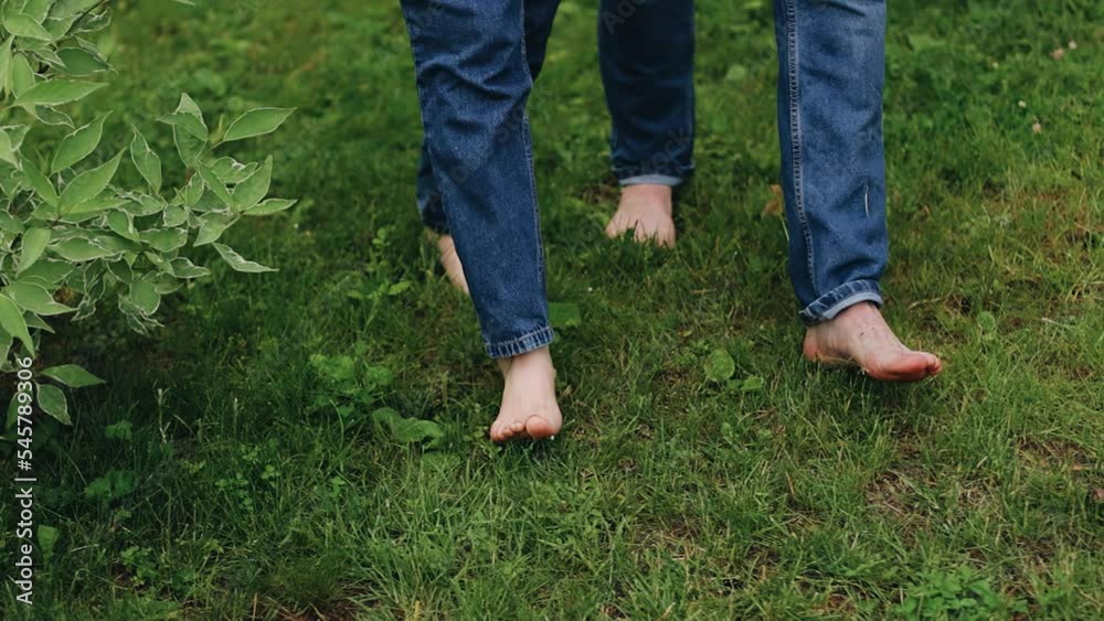 The feet of lovers who walk barefoot on the grass. The camera shoots close-up in slow motion The feet of lovers who walk barefoot on the grass. The camera shoots close-up in slow motion