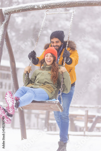 Playful couple swinging while on winter vacation