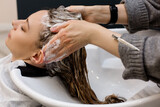 Woman with hairdresser washing head at hair salon