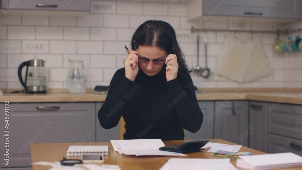 starting doing paperwork at home woman put on glasses reading paper letter bills sit kitchen table. calculator magnifier smartphone money bank invoices on table. family budget concept starting doing paperwork at home woman put on glasses reading paper letter bills sit kitchen table. calculator magnifier smartphone money bank invoices on table. family budget concept
