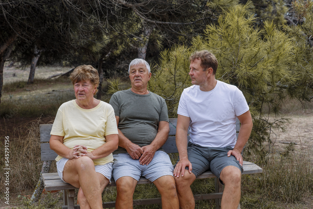 Elderly parents with an adult son walk in the park, communication and care for loved ones Elderly parents with an adult son walk in the park, communication and care for loved ones