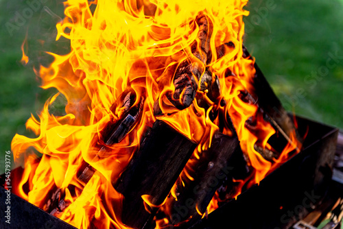 A large fire made of planks. Firewood in a bright flame. Firewood burns brightly in an iron grill.