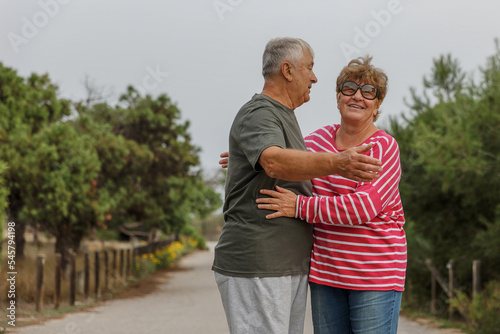 Happy elderly couple embracing in park on sunny day, love together in Valentines day concept, senior couple anniversary