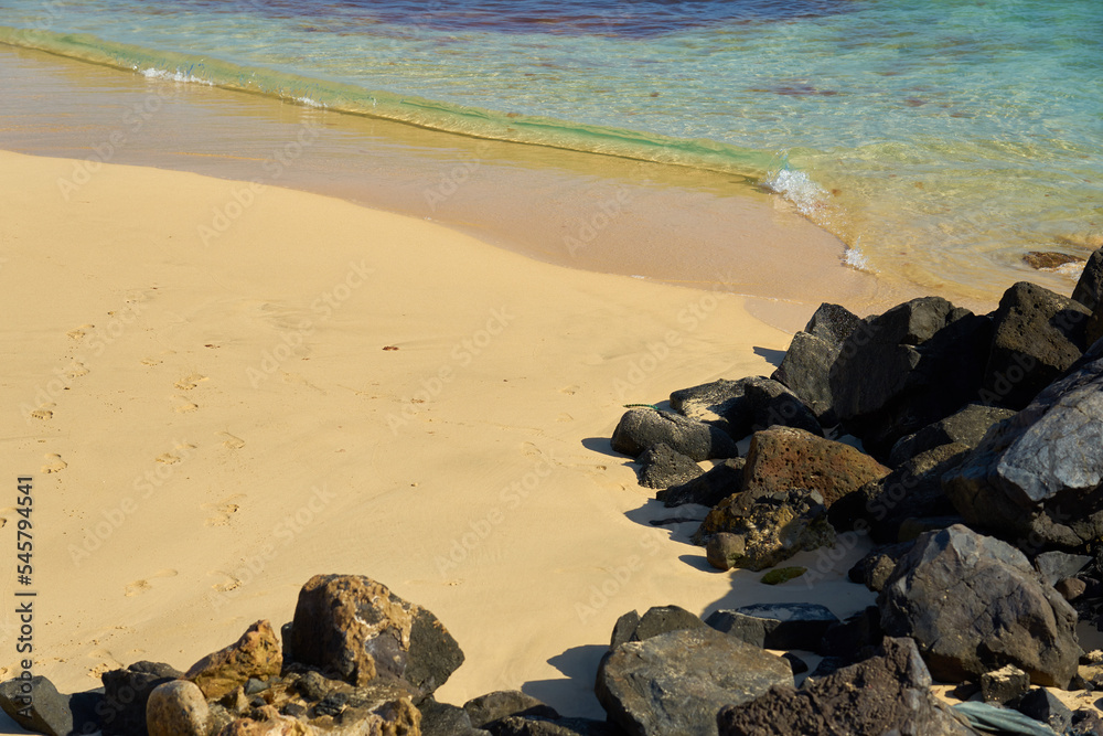 Rocks and waves on a sandy tropical beach.
