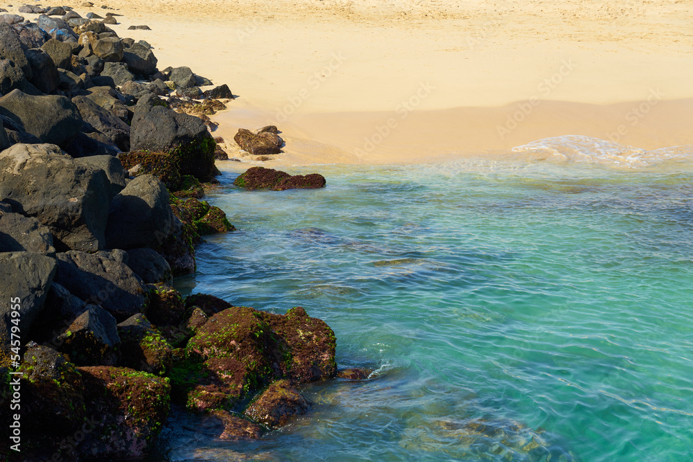 Rocks and waves on a sandy tropical beach.