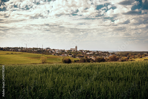 Vista da cidade de Santo Cristo, pequena cidade no interior do Rio Grande do Sul, campos, potreiros e plantações. Céu com nuvens (ID: 545795300)