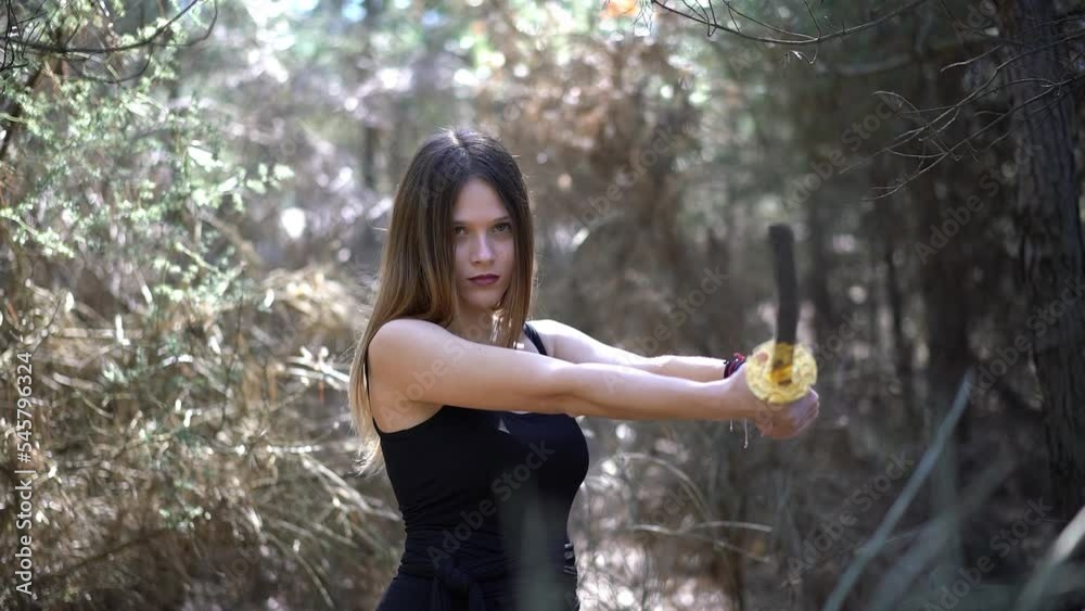Young beautifull woman in the forest holding a sword Young beautifull woman in the forest holding a sword