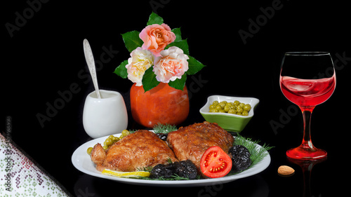 Chicken baked in sweet sauce with prunes, vegetables and wine on a black background. Selective focus