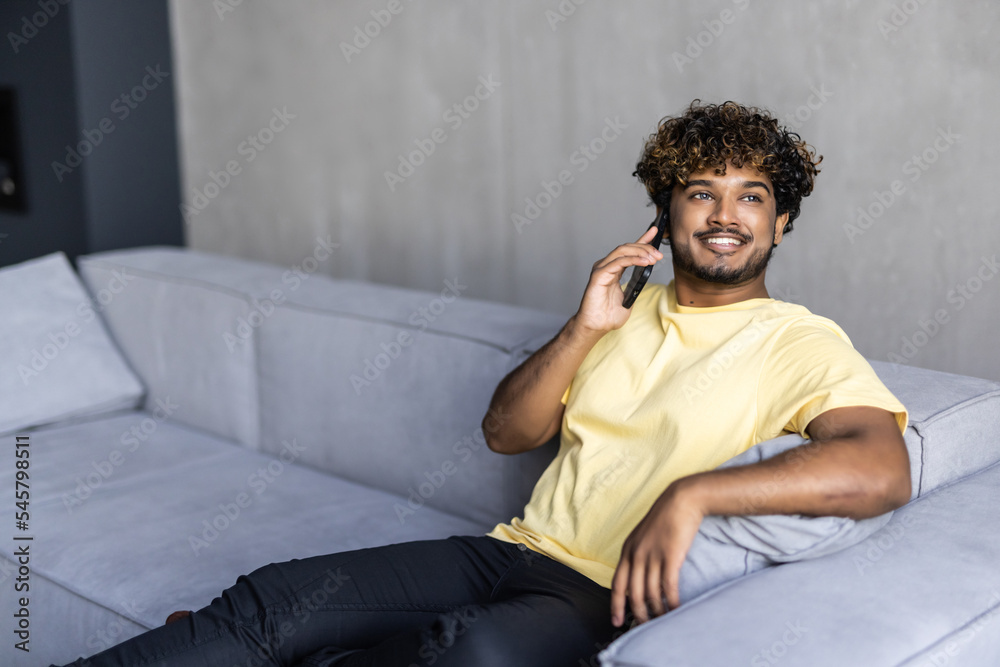 technology, communication and people concept. Indian happy smiling man calling on smartphone at home technology, communication and people concept. Indian happy smiling man calling on smartphone at home