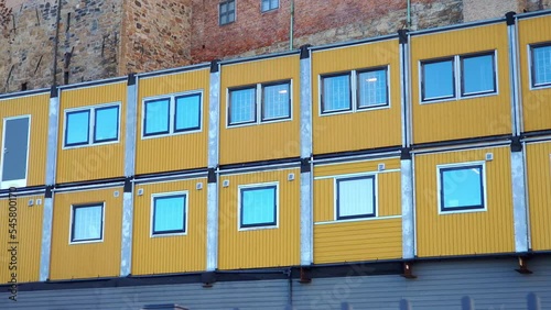 Container homes and offices on a construction site - yellow shipping containers with windows, used as temporary dwelling units for workers and as offices.