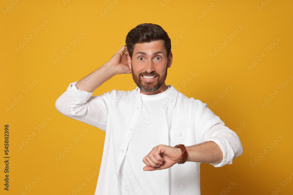 Emotional man checking time on orange background. Being late concept Emotional man checking time on orange background. Being late concept
