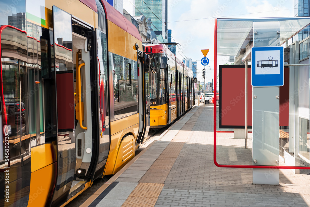 Modern streetcars near tram stop on sunny day. Public transport - obrazy, fototapety, plakaty 