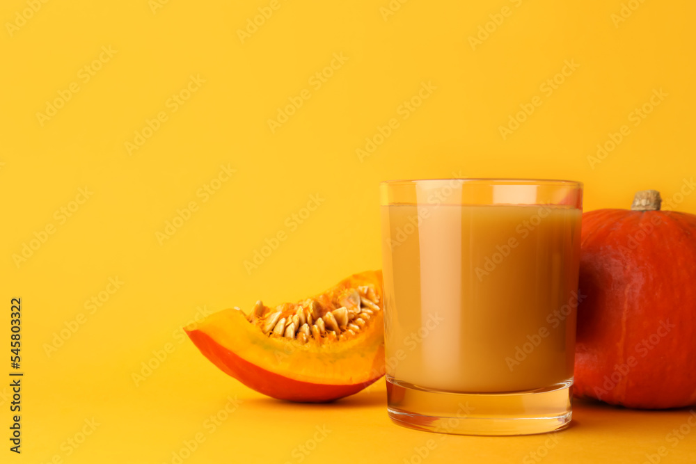 Tasty pumpkin juice in glass, whole and cut pumpkins on orange background. Space for text Tasty pumpkin juice in glass, whole and cut pumpkins on orange background. Space for text