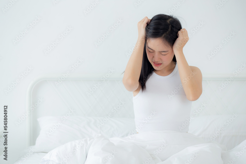 Young asian woman sitting on bed pain headache in the bedroom at home, unhappy female exhaustion and sick headache, anxiety and unwell, dizziness and disorder, medical and health concept. Young asian woman sitting on bed pain headache in the bedroom at home, unhappy female exhaustion and sick headache, anxiety and unwell, dizziness and disorder, medical and health concept.