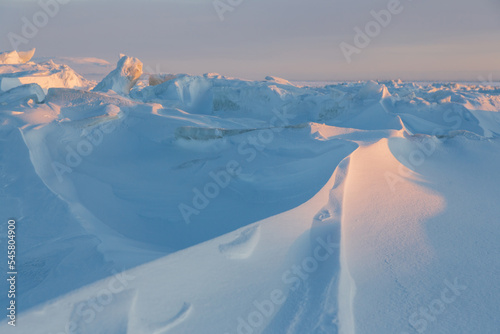 Winter arctic landscape. Ice hummocks on the frozen sea in the Arctic. View of snow and ice at sunset. Cold frosty winter weather. Harsh polar climate. Amazing nature in the far north in the Arctic. photo