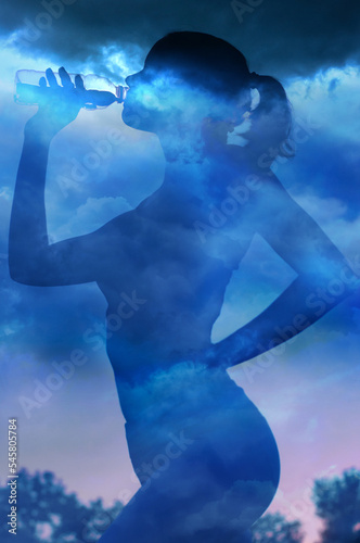 Silhouette of girl drinking water from plastic bottle against cloudy sky on a summer day