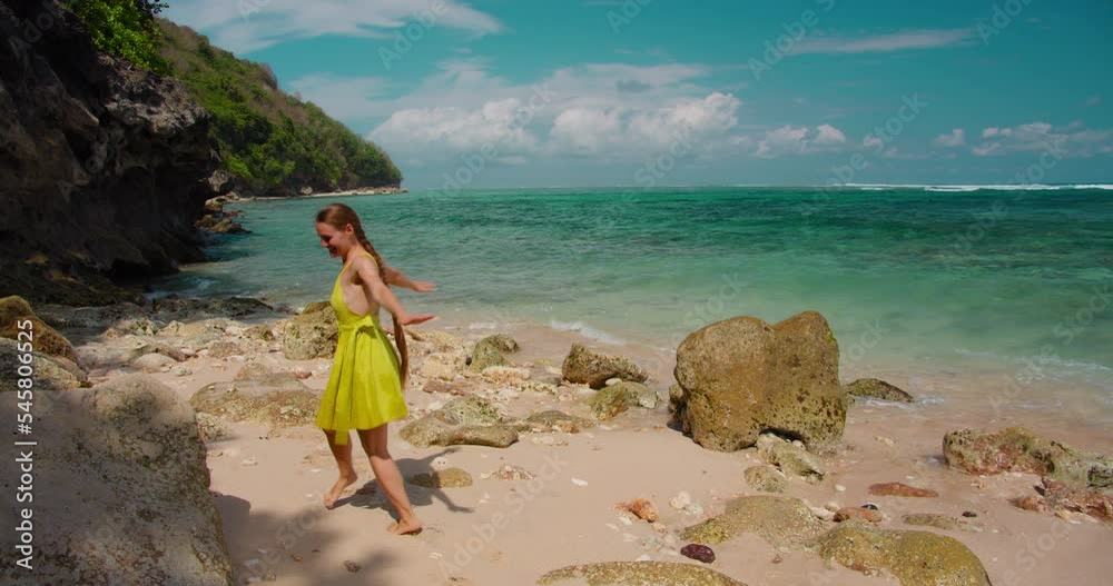 Tourist woman walking dancing on sandy Green Bowl Beach, Bali Island, Indonesia. Alone happy girl enjoys along the coastline. Ocean seaside. Sea waves crash foam. Relax.