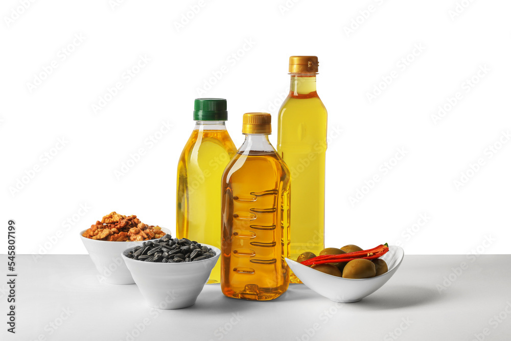 Bottles of different cooking oils, sunflower seeds, walnuts and olives on white background Bottles of different cooking oils, sunflower seeds, walnuts and olives on white background