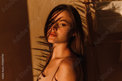 Stylish photo of a female model in the shade of a palm leaf.