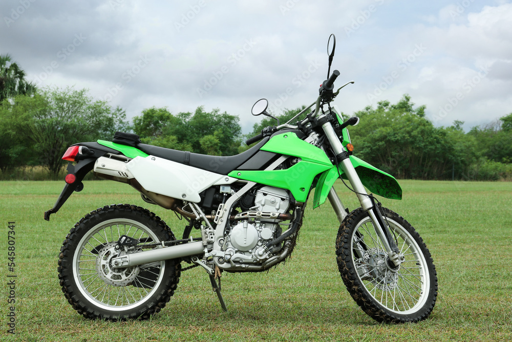 Stylish cross motorcycle on green grass outdoors