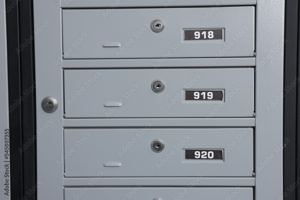 Closed metal mailboxes with keyholes and sequence numbers indoors Closed metal mailboxes with keyholes and sequence numbers indoors