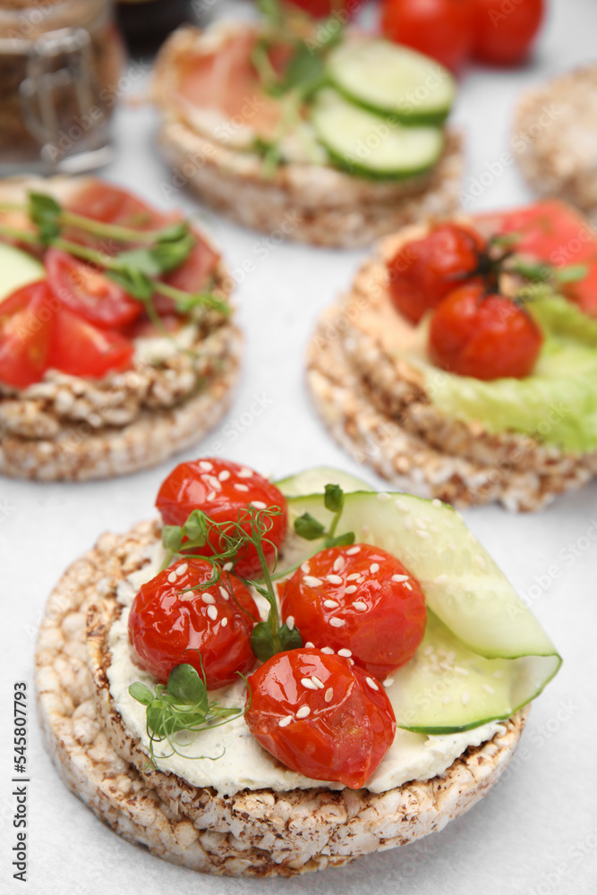 Crunchy buckwheat cakes with cream cheese, tomatoes and cucumber slices on white table, closeup Crunchy buckwheat cakes with cream cheese, tomatoes and cucumber slices on white table, closeup