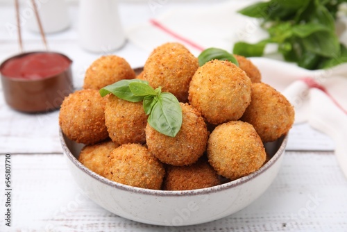 Bowl of delicious fried tofu balls with basil on white wooden table